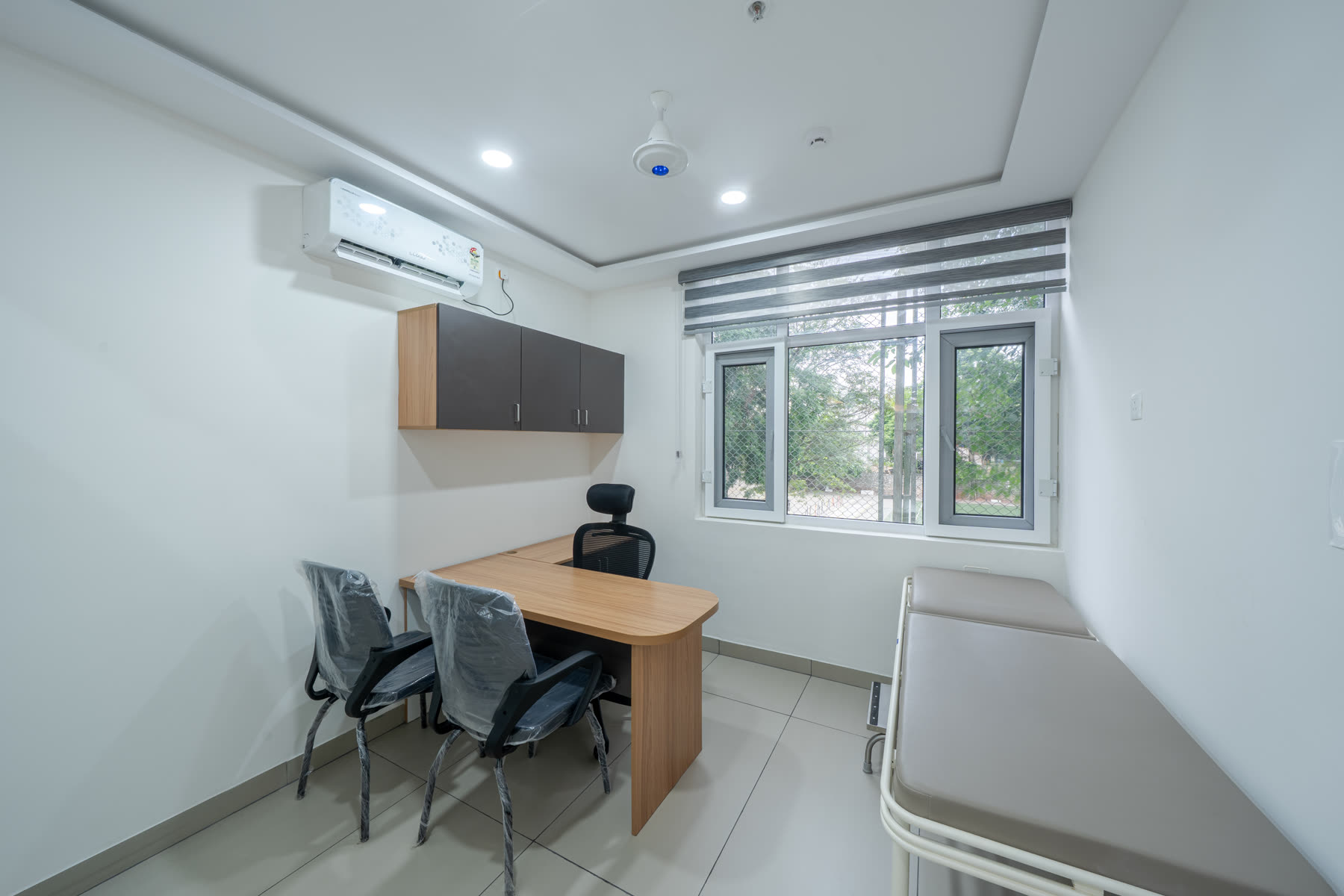 Healthcare consultation room with doctor's desk, examination couch and patient chairs